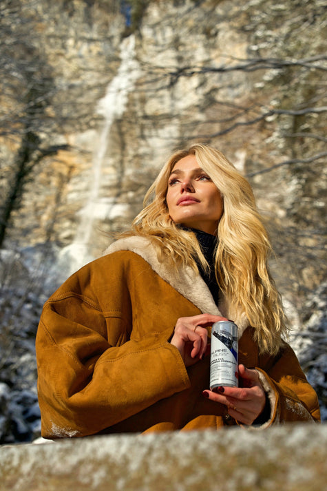 Woman holding a can of Alpine Bliss low calorie energy drinks with Alpine water and natural fruit juice.